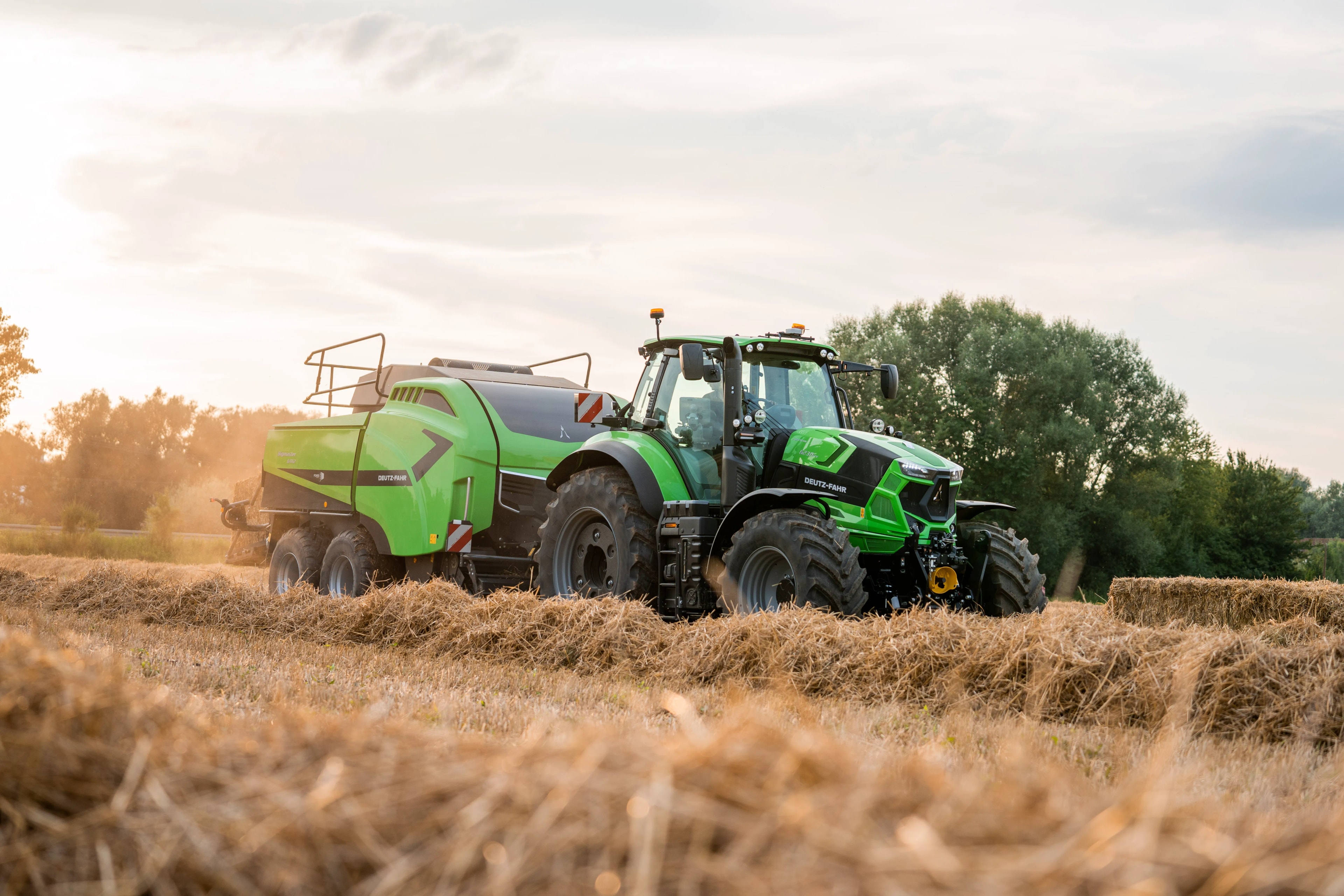 Traktor DEUTZ-FAHR s lisem při sklizni slámy na poli